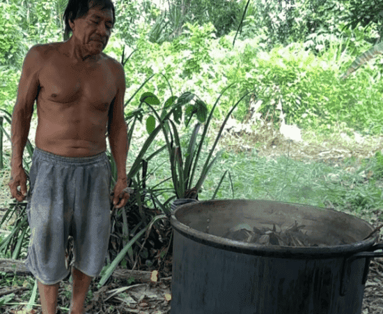 Man cooking outdoors at Soi Rawa retreat in lush greenery.