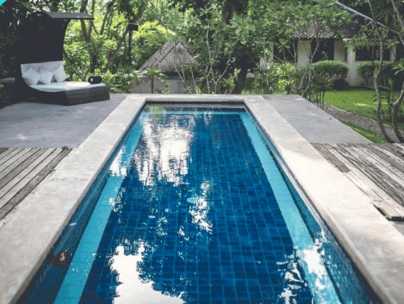 Serene outdoor pool at a healing retreat surrounded by lush greenery.