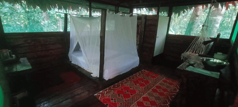 Cozy bedroom at Naturalia Retreat Center with mosquito net and rustic decor.
