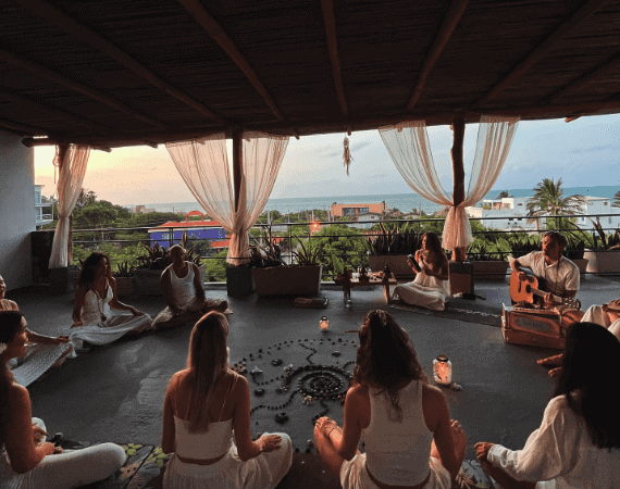 Group meditation session at Ancestral Retreats with ocean view backdrop.
