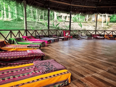Outdoor retreat space with colorful mats and cushions under a thatched roof at Katari Center.