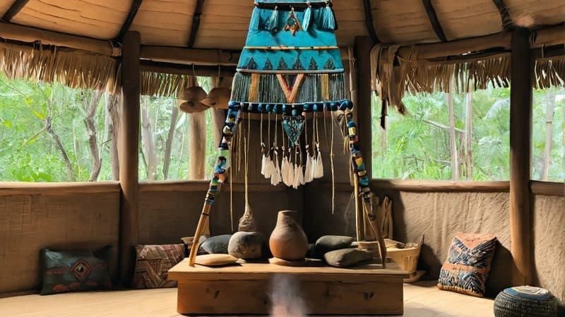 Altar for tobacco cleansing ritual inside a traditional hut with fire pit and spiritual artifacts.