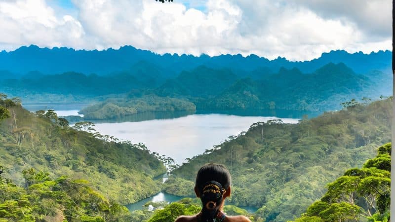 Peaceful woman practicing meditation in tropical retreat setting with scenic mountain view.