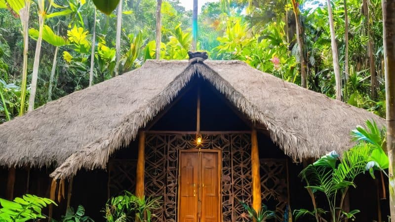 Peaceful jungle retreat with traditional thatched roof and lush greenery. Perfect for relaxation and.