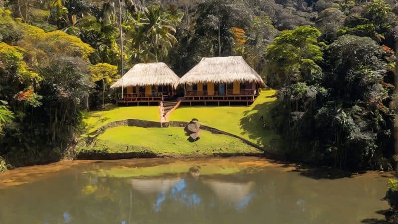 Beautiful jungle retreat with traditional huts near a tranquil lake.