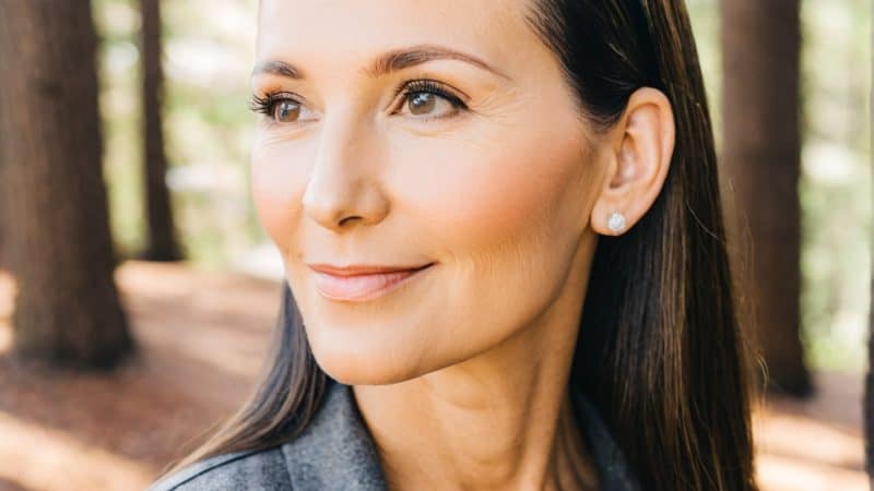 Relaxed woman in a forest, enjoying a peaceful retreat experience.