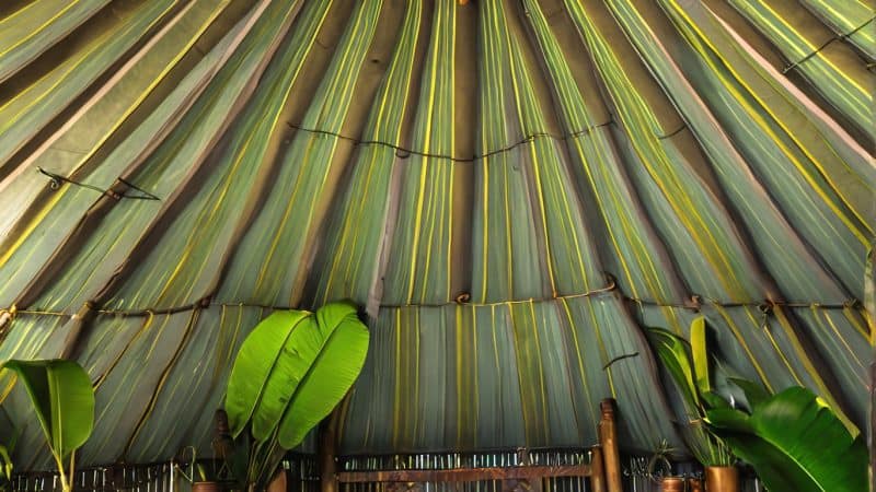 Cozy bedroom inside a traditional tropical retreat with lush greenery and vibrant decor.
