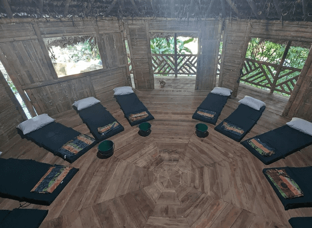 Yoga retreat hut with mats and cushions in a bamboo structure.