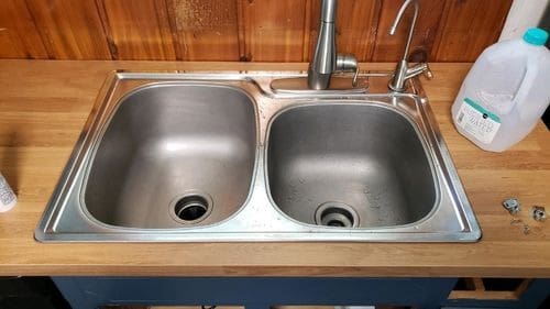 Stainless steel double sink with modern faucet on wooden countertop, relevant for plumbing repairs and maintenance services in Knoxville.
