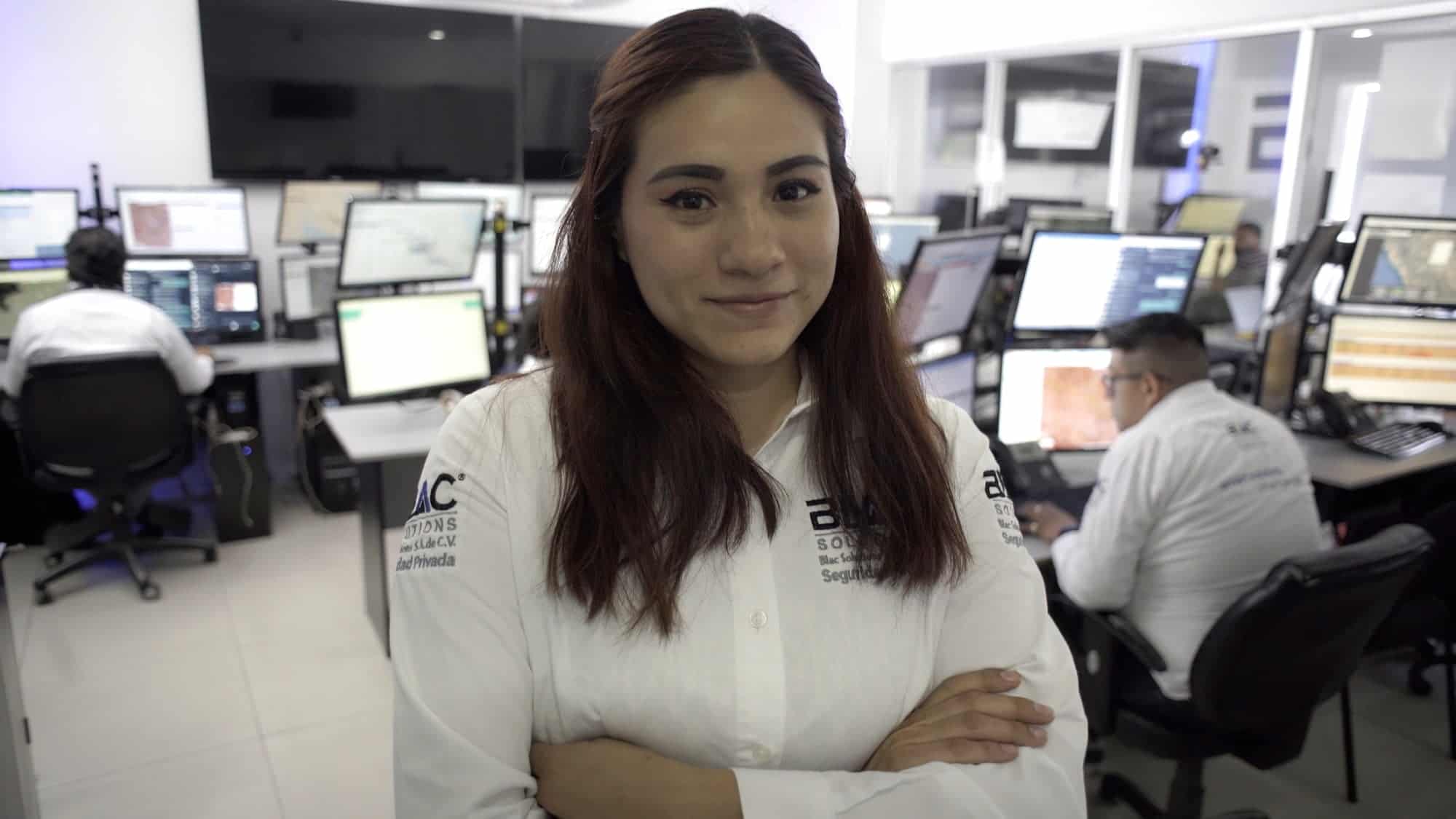 Mujer en centro de control con monitoreo satelital y gestión de riesgos.