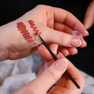 Lipstick swatches and application on hand, highlighting bold red lipstick colors.