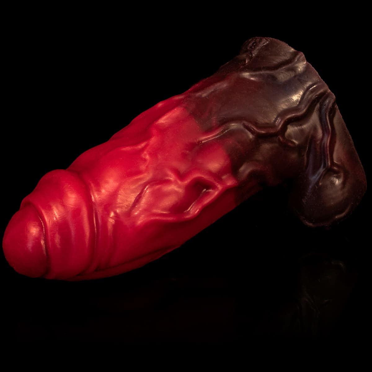 Pinto grande e vermelho de silicone macio da Monster D Toys deitado sobre fundo preto.