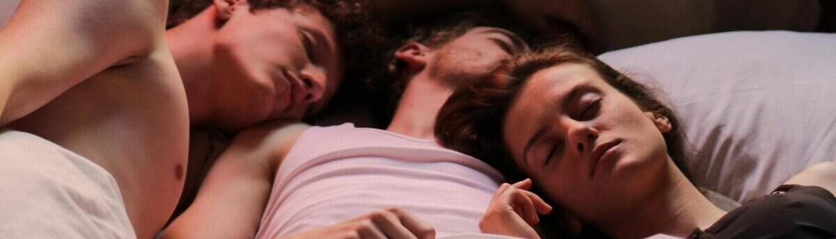 trisal formado por dois homens e uma mulher deitados na cama após dupla penetração