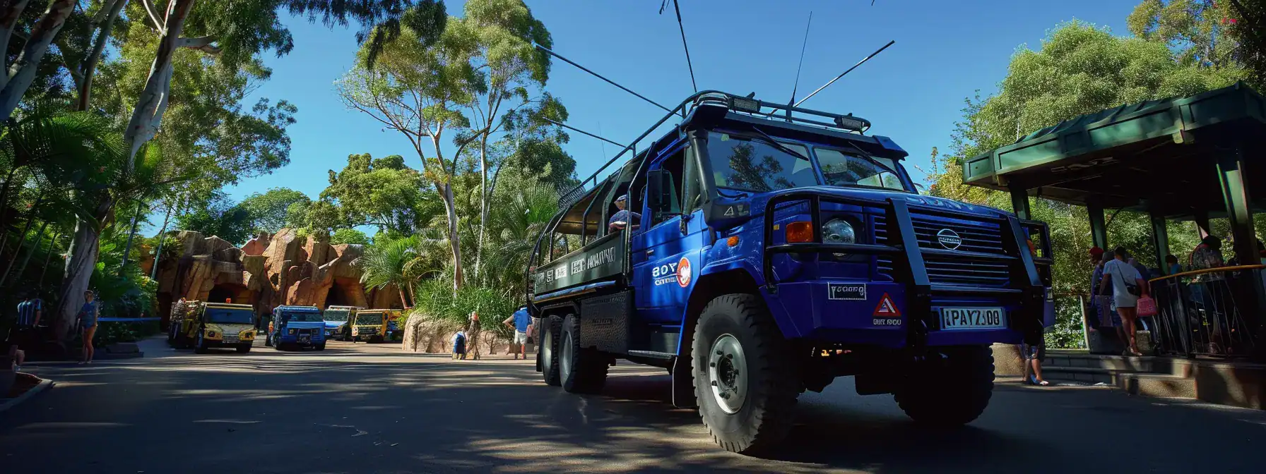 a luxurious blue diamond transfer vehicle parked outside australia zoo with a diverse fleet in the background, ready to cater to a family's wildlife adventure preferences.