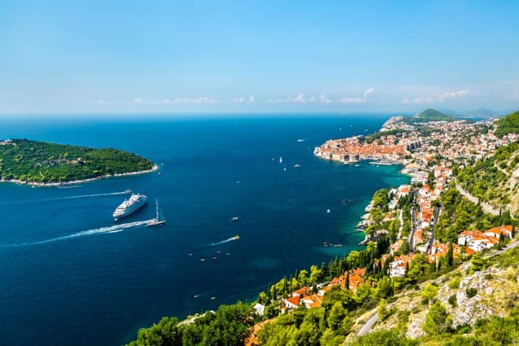 aerial view of Old Town Dubrovnik with many boats and a cruiser floating around.