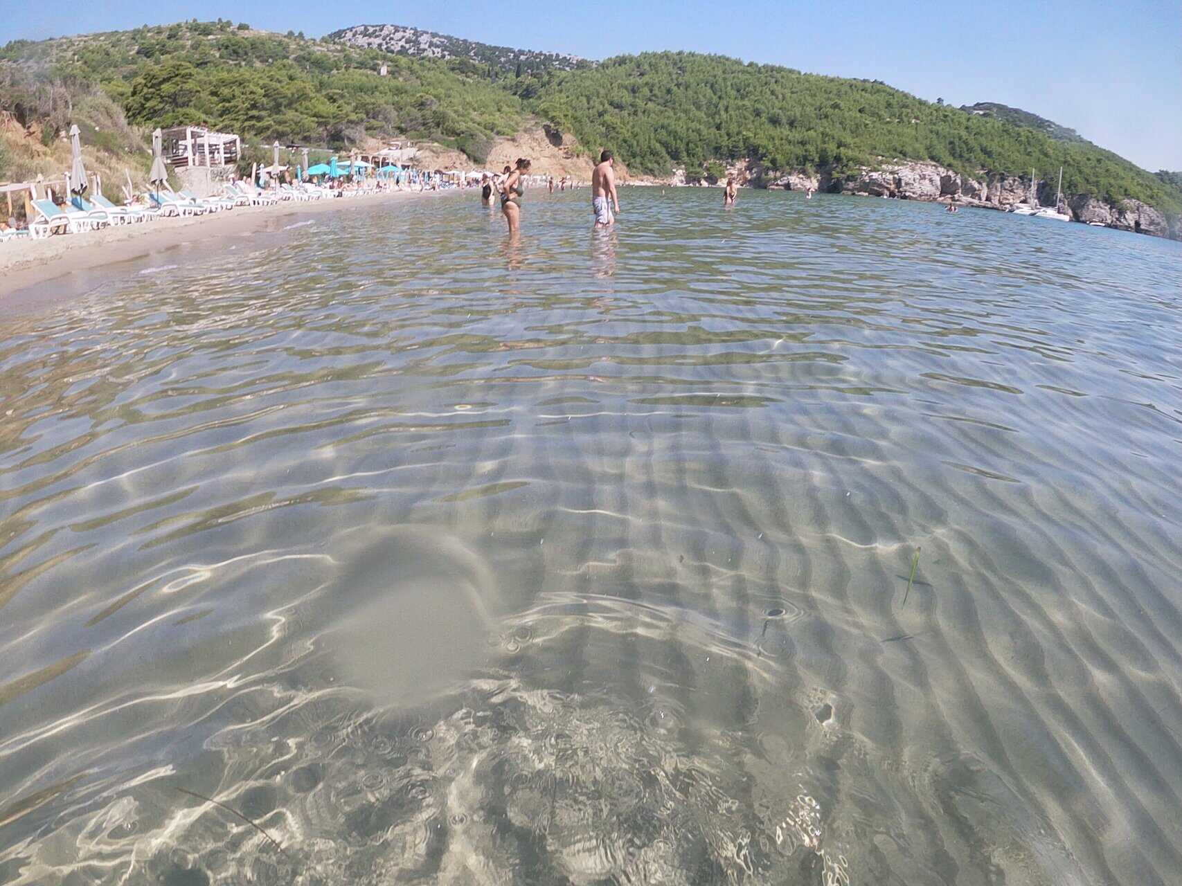 Tour guests walking on the sandy shore of Šunj