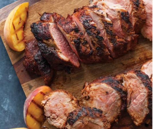 Succulent, perfectly grilled steaks with juicy, tender meat and flavorful charred exterior, served with grilled peaches on a rustic wooden cutting board.