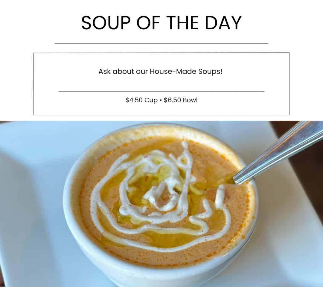 Creamy bowl of homemade tomato soup with a swirl of cream on top, served in a white bowl with a silver spoon, highlighting fresh, flavorful ingredients from Bodacious Shops.