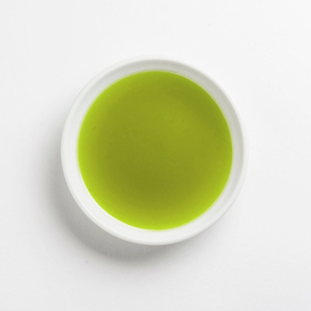 Bright green matcha tea in a white ceramic cup, top-down view, minimalistic style.
