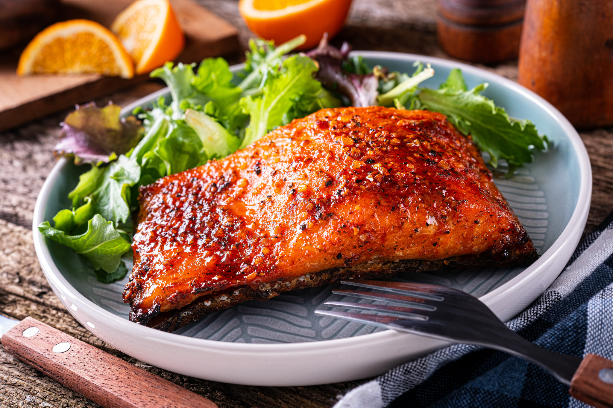 Juicy, grilled salmon fillet with crispy seasoned exterior served with fresh mixed greens on a rustic wooden table. Perfect for healthy seafood lovers and dinner recipes.