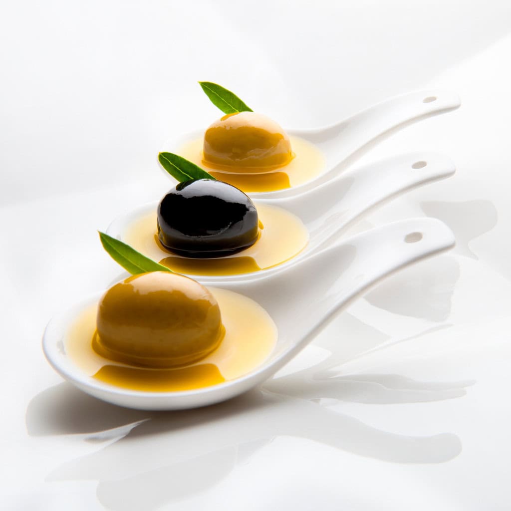 Delicious caramel and chocolate puddings with fresh green leaves on white spoons for elegant dessert presentation.