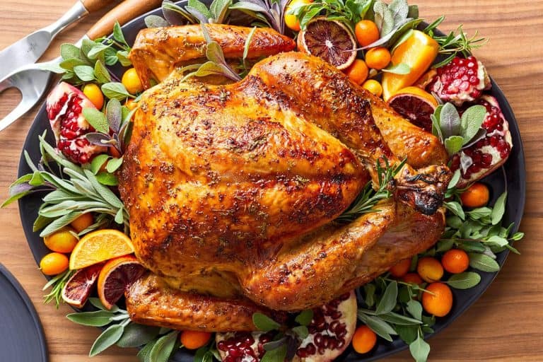 Roast chicken garnished with herbs, citrus, and pomegranate on a platter, perfect for holiday feasts, family dinners, and special occasions.