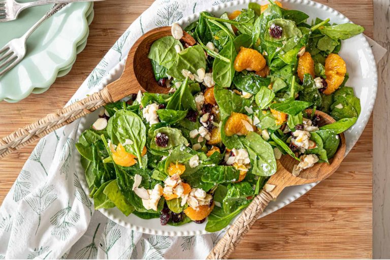 Fresh healthy salad featuring mixed greens, orange segments, feta cheese, and almonds, presented on a white platter. Ideal for nutritious dining, summer recipes, and farm-to-table cuisine.