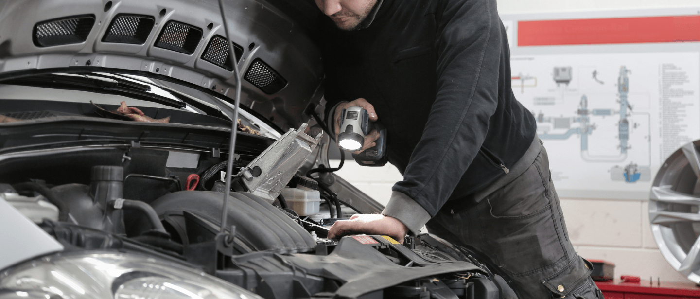 Auto mechanic inspecting car engine at Boise Muffler Auto Repair.