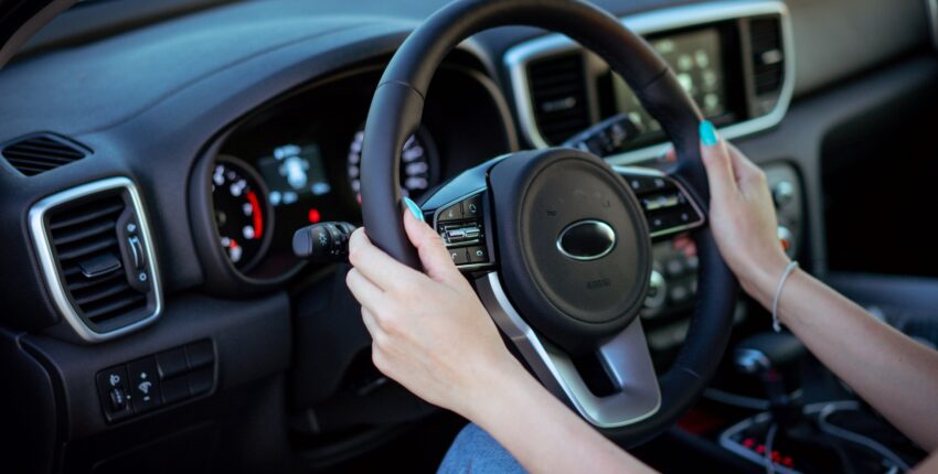 Person holding steering wheel inside vehicle for auto repair service.