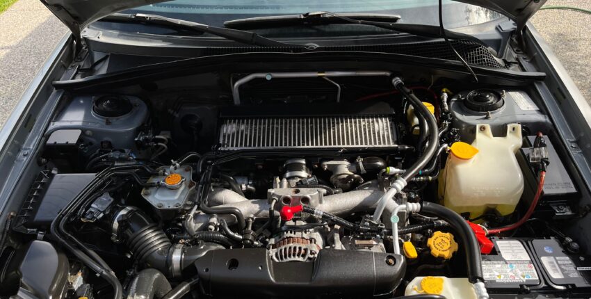 Car engine bay with visible engine components and fluid reservoirs.