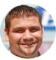 A person with short hair and a beard smiles confidently, perhaps contemplating the future joys of HVAC careers, against a blurred outdoor background.