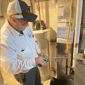 A technician in a white uniform checks a pipe with a handheld device, embodying the thorough professionalism that Bonfe Insider highlighted back in October 2022, within a utility room equipped with a furnace and water heater.