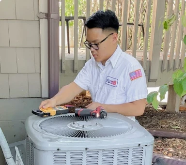Person in uniform working on an outdoor air conditioning unit with tools.