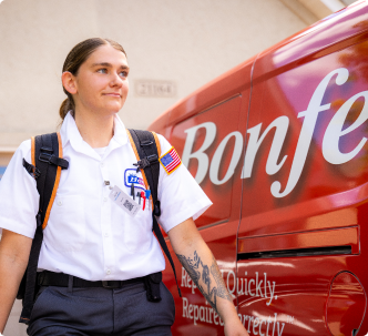 A uniformed technician with a backpack stands next to a red Bonfe service van, wearing a name badge and an American flag patch on her sleeve, ready to discuss your Membership Plan and answer any Terms & Conditions questions.