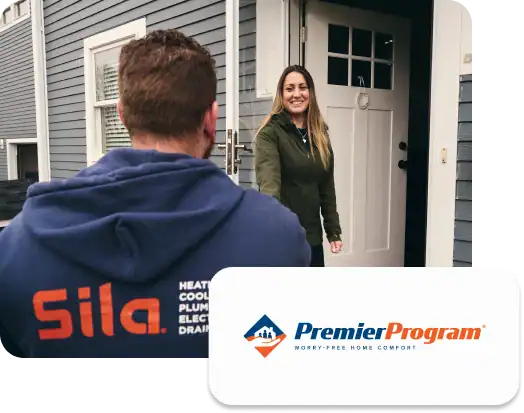A technician wearing a "Sila" hoodie greets a smiling woman at her front door, showcasing the Premier Pro Program logo in the lower right corner.
