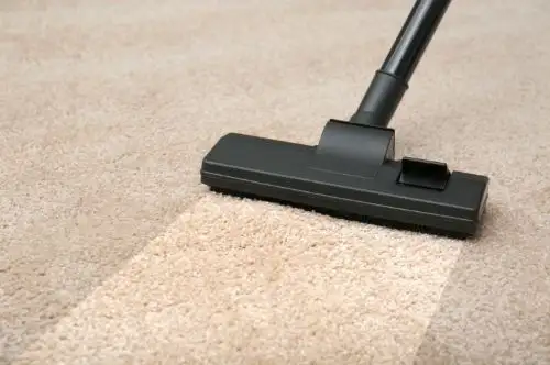 Vacuum cleaner on beige carpet cleaning line