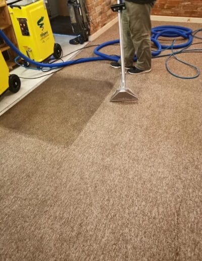 Person cleaning carpet with steam cleaner machine.