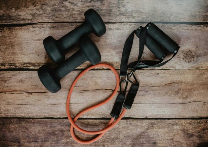 Dumbbells, resistance band, and jump rope on wooden floor, gym workout equipment for fitness training, strength building, and exercise at Bay-O-Vista Swim & Tennis Club.