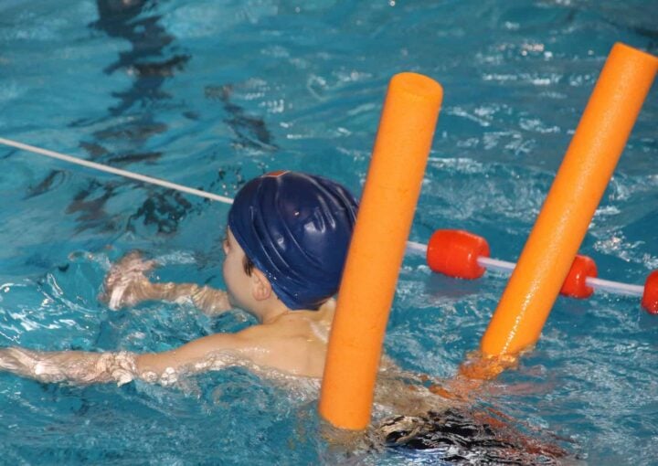 Child taking swim lessons with instructor in the Bay-O-Vista pool - learning water safety skills in San Leandro