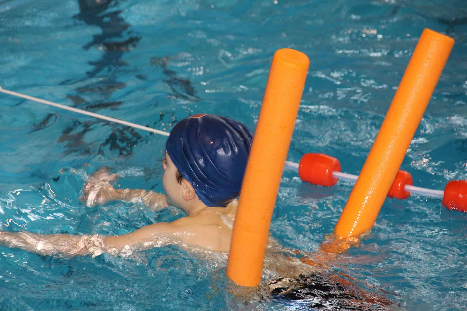 Child taking swim lessons with instructor in the Bay-O-Vista pool - learning water safety skills in San Leandro
