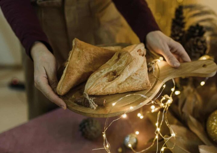 Golden-baked puff pastry triangles served on a wooden platter with festive fairy lights, ideal for holiday gatherings at Bay-O-Vista Swim & Tennis Club.