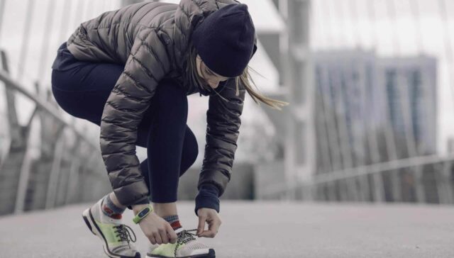 Active woman tying her running shoes outdoors in an urban setting.