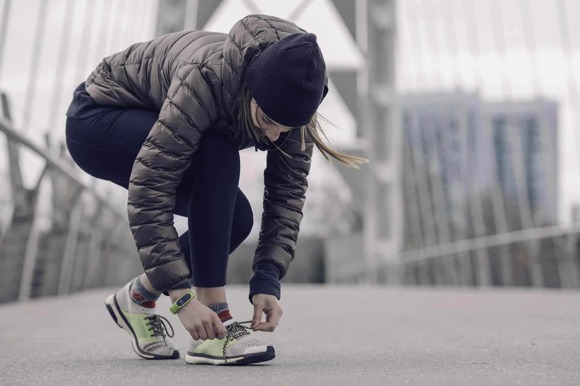 Active woman tying her running shoes outdoors in an urban setting.