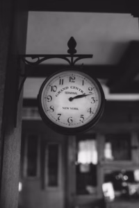 Black and white photo of a round wall-mounted clock labeled "Grand Central Terminal New York," showing the time as 5:00—captured with the timeless artistry of an Eau Claire wedding photographer.