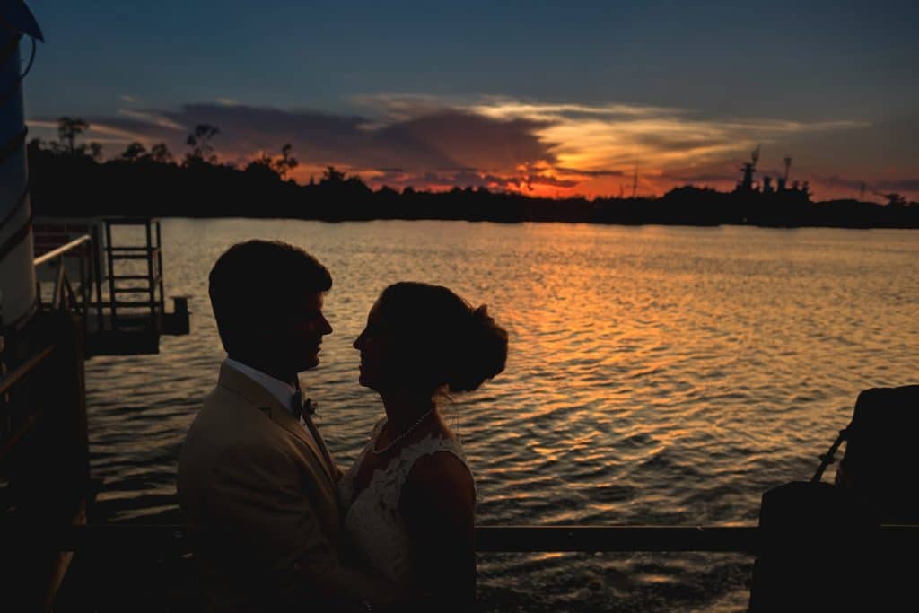 A wedding at St. Thomas Preserve with a bride and groom standing on a dock at sunset.