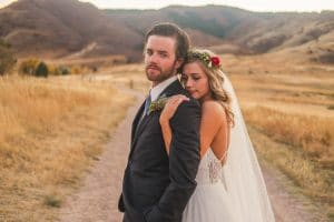 A Littleton Wedding Photographer captures a bride and groom posing on a dirt road in the mountains.