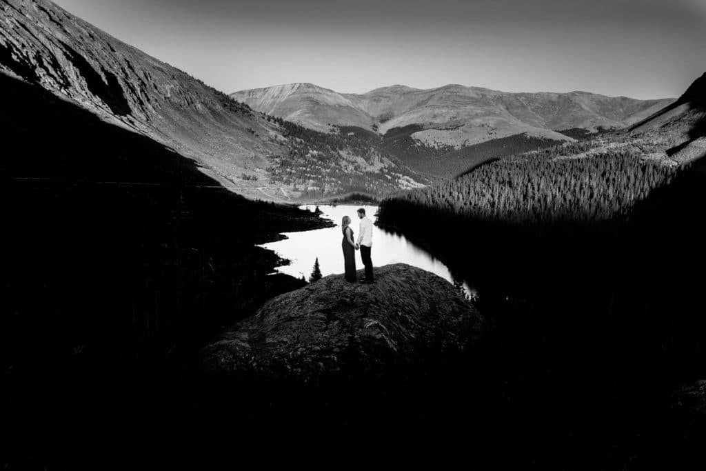 A black and white photo of a person standing on top of a mountain.