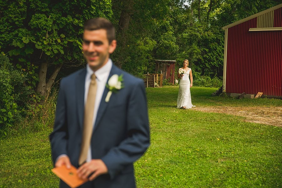A bride and groom standing in front of a red barn.