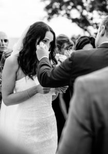 groom wiping tears of crying bride on top of Grandad Bluff in La Crosse WI
