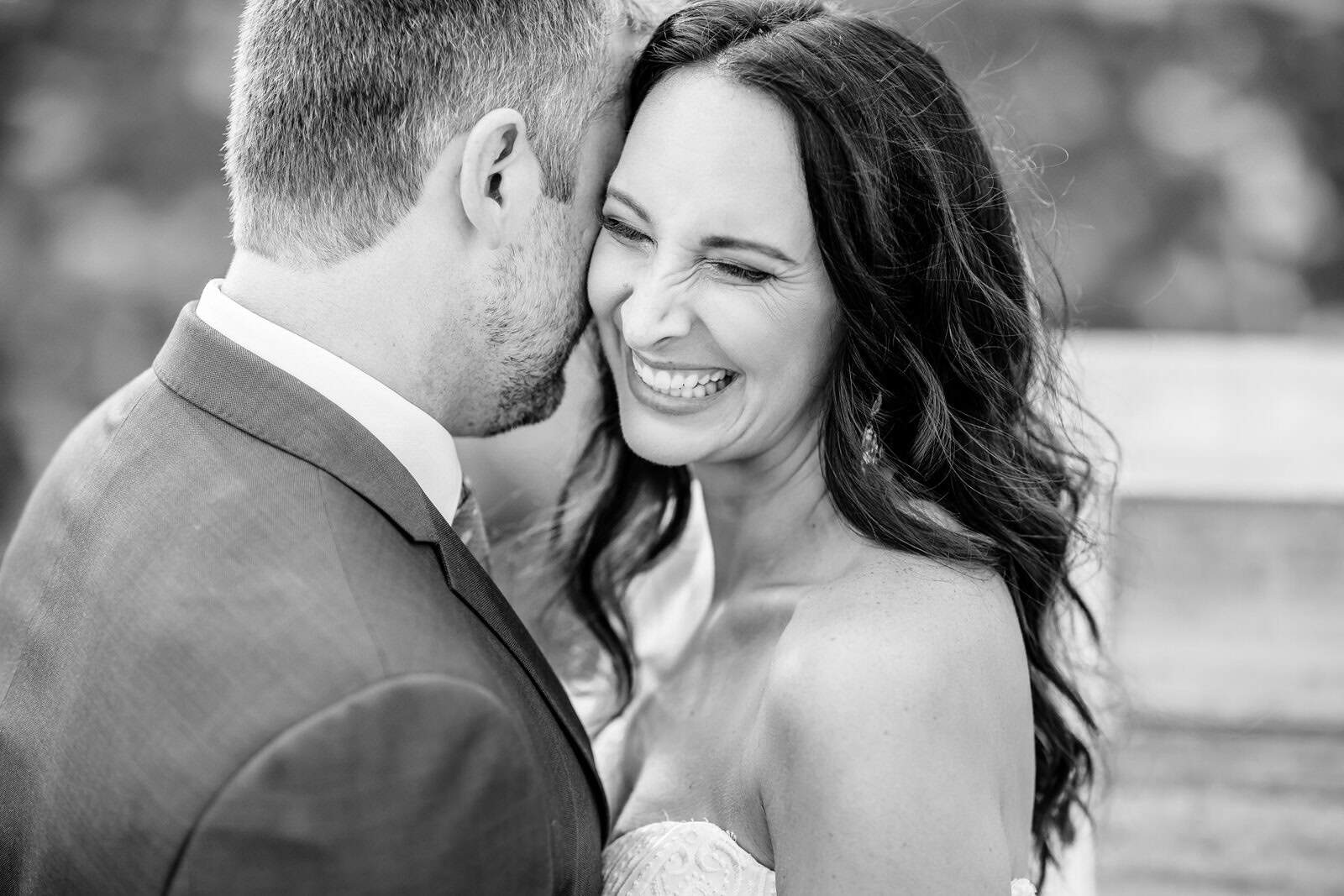 A black and white photo of a bride and groom sharing a kiss.